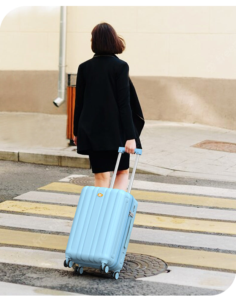 Person pulling a light blue suitcase on a sidewalk