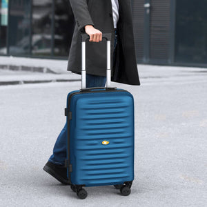 Person holding a blue suitcase outdoors