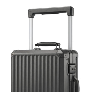 Close-up of a dark grey hard-shell suitcase showing its telescopic handle, top carry handle, and vertical ridge design.