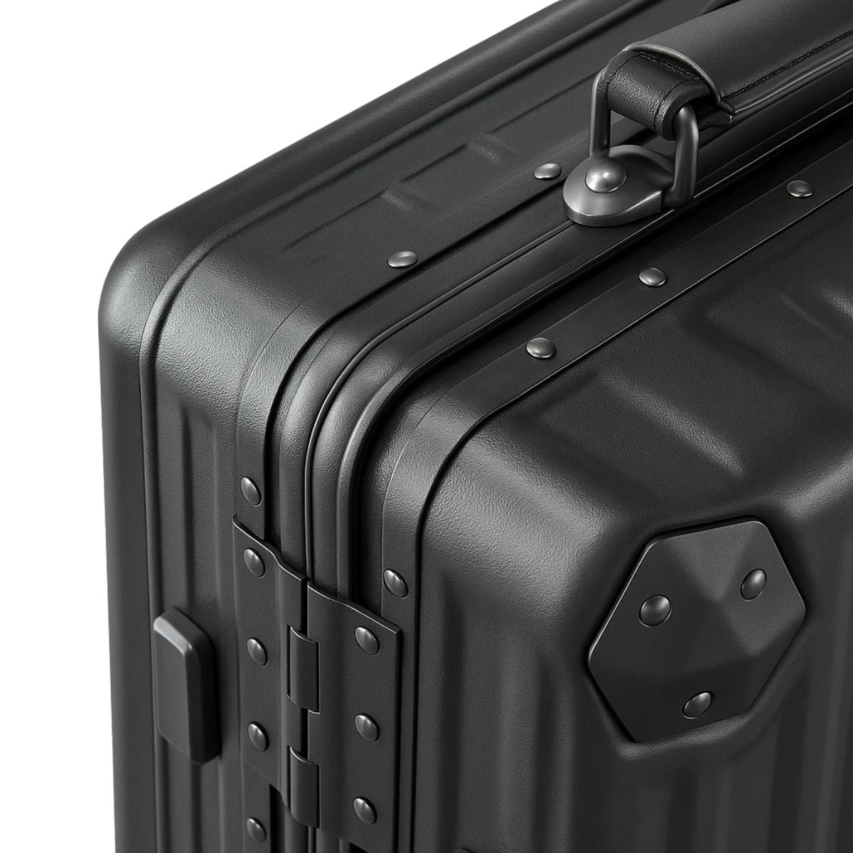 Close-up of a black hard-shell suitcase showing reinforced corners, rivet details, and a sturdy top carry handle.
