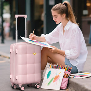 Woman sitting on a street corner drawing with a pink suitcase and art supplies nearby