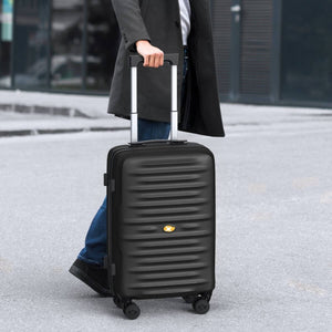 Person holding a black suitcase outdoors