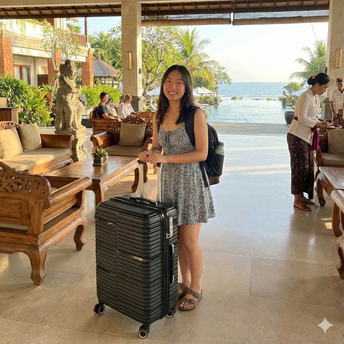 StratoLine black suitcase in hotel lobby setting with traveler and tropical resort background.