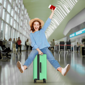 Woman sitting on a green suitcase in an airport, holding a red passport